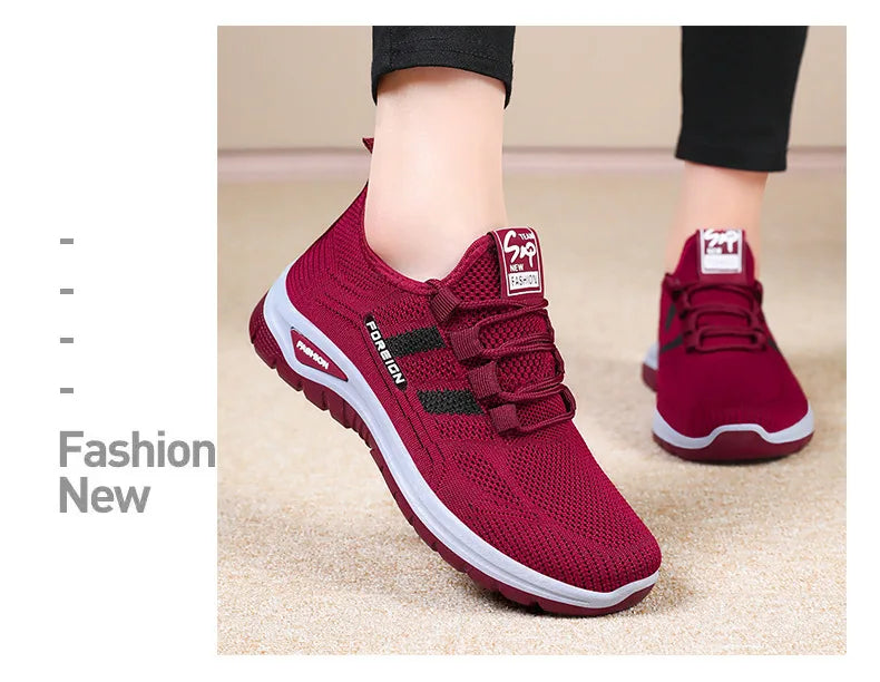 Shows a person wearing comfortable red mesh sneakers with white soles.
