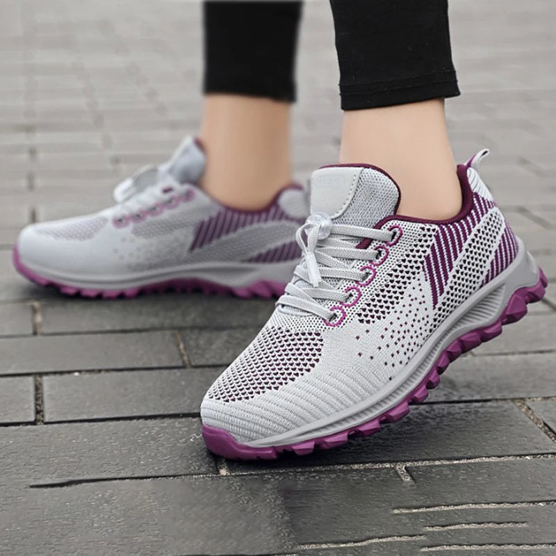 Person wears grey and purple athletic running shoes on a brick sidewalk.
