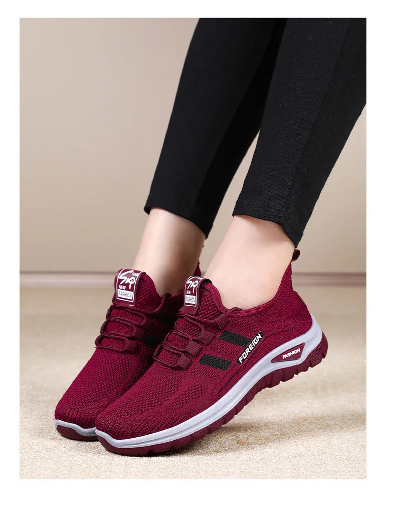 Woman models comfortable, burgundy "FOREIGN" branded walking sneakers paired with black leggings.
