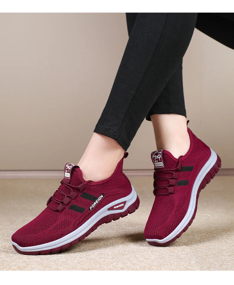 Person models comfortable maroon-colored walking shoes with black leggings.
