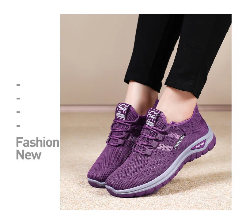 A person models comfortable purple knit fashion sneakers with grey soles.
