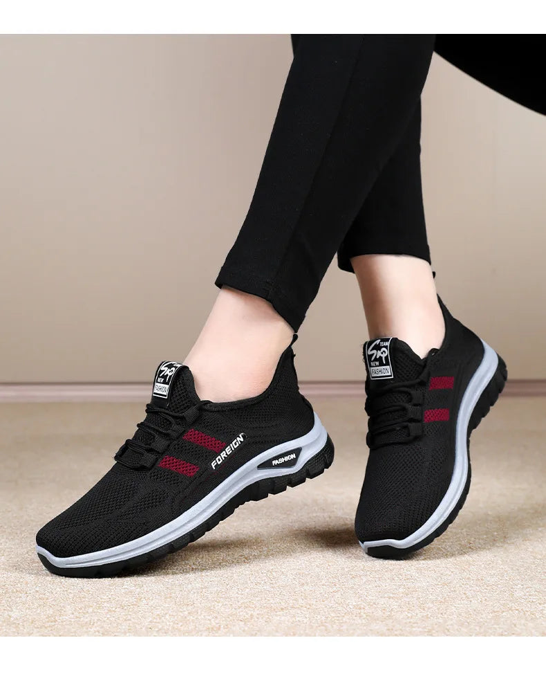 A person models comfortable black and red "FOREIGN" fashion sneakers with black leggings.
