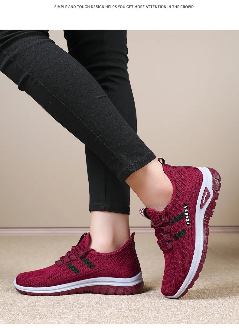Person wears comfortable maroon athletic shoes with black accents and white soles, showcasing the stylish design.
