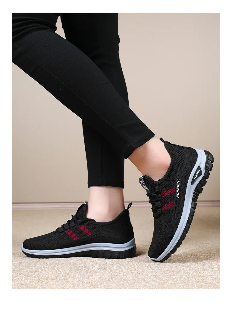 Woman models comfortable black walking shoes with red stripes and light gray soles.
