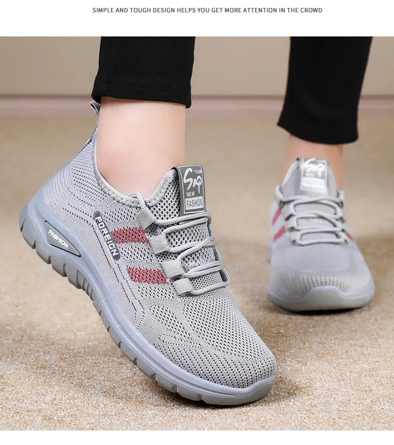 A person models gray "Foreign" athletic walking shoes with red stripes, showcasing the breathable knit design and comfort for fashion.
