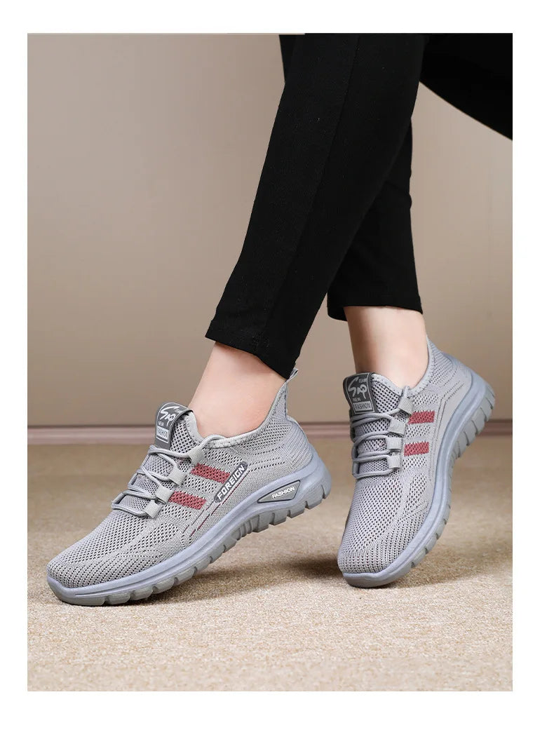 A person models stylish grey mesh walking shoes with red stripes and the word "FOREIGN" printed on the side.

